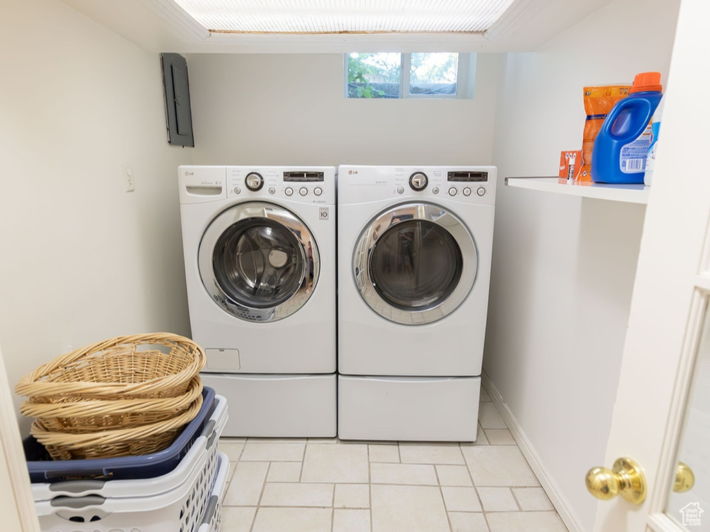 Clothes washing area with washing machine and dryer and light tile patterned floors