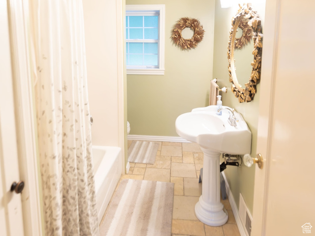 Bathroom featuring tile patterned flooring, toilet, and shower / tub combo