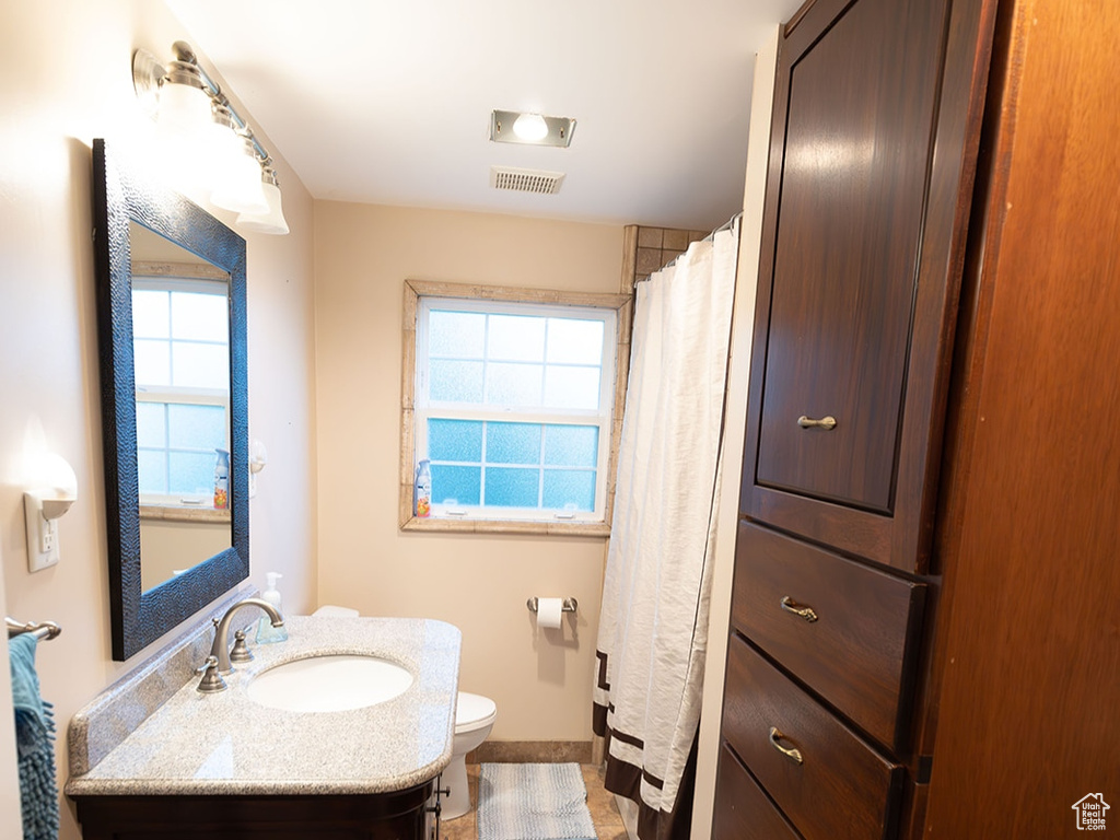 Bathroom featuring vanity, tile patterned floors, a wealth of natural light, and toilet