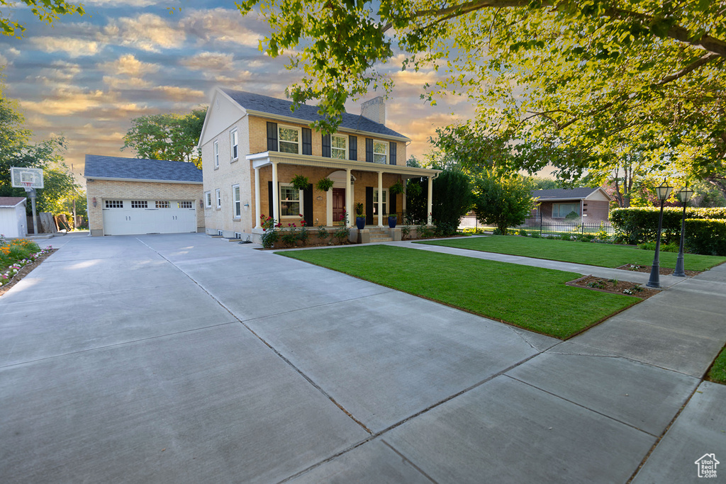 View of front of house with a garage, covered porch, and a lawn