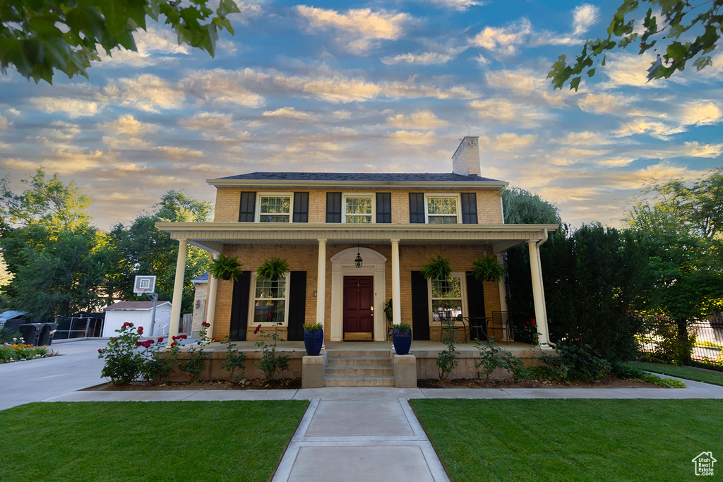 View of front of house with covered porch, an outdoor structure, and a lawn