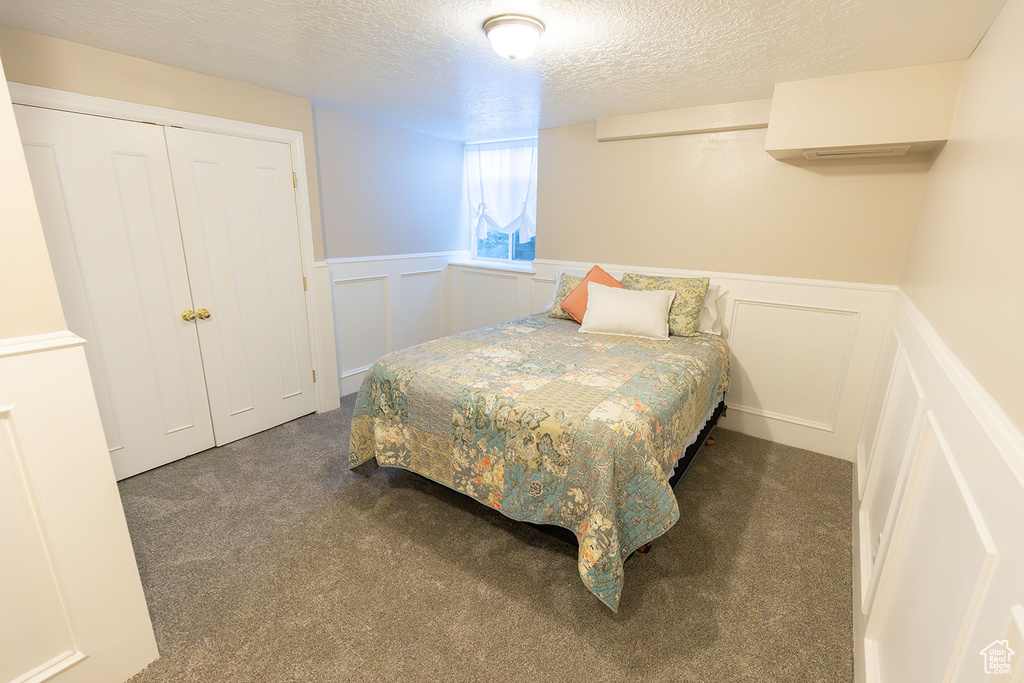 Bedroom featuring carpet, a closet, and a textured ceiling