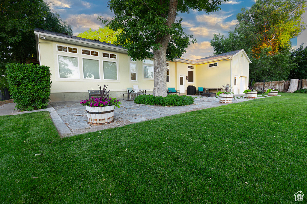 Back house at dusk featuring a patio area and a yard