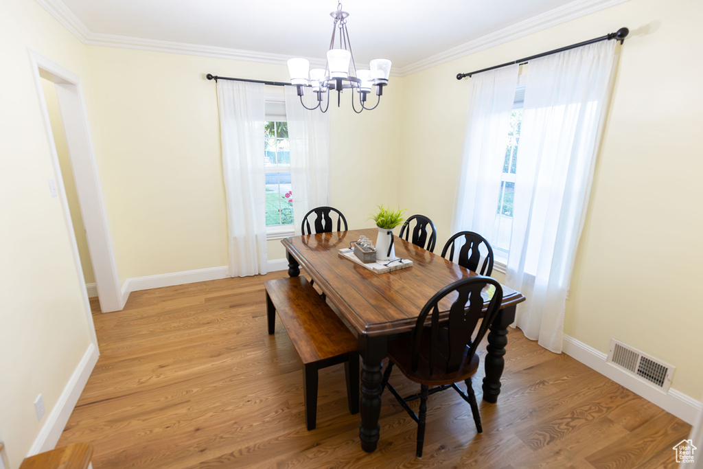 Dining room with a notable chandelier, crown molding, and hardwood / wood-style floors