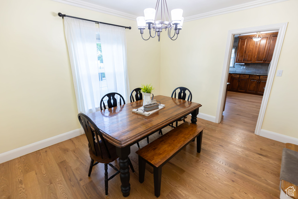 Dining area featuring an inviting chandelier, light hardwood / wood-style flooring, and ornamental molding