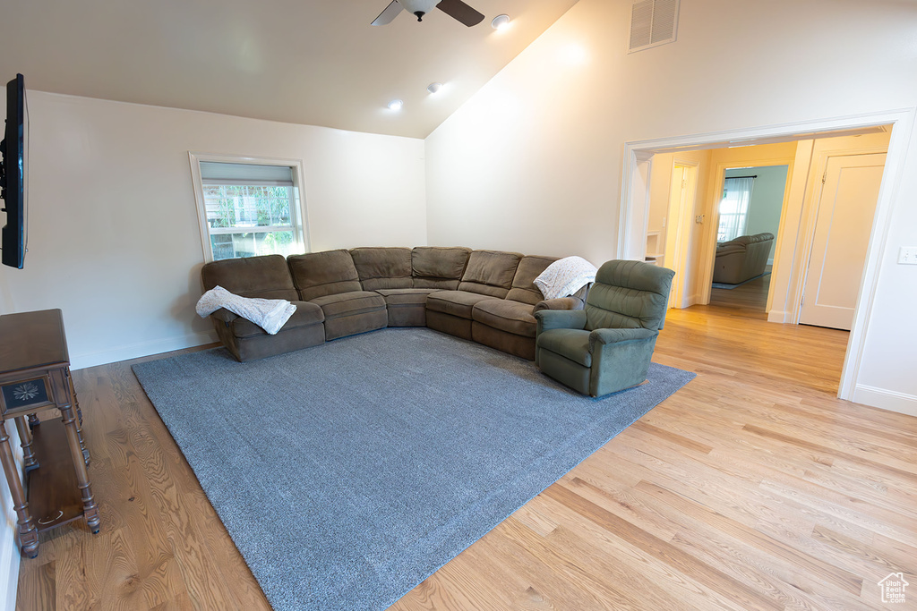 Living room featuring light hardwood / wood-style floors, ceiling fan, and high vaulted ceiling