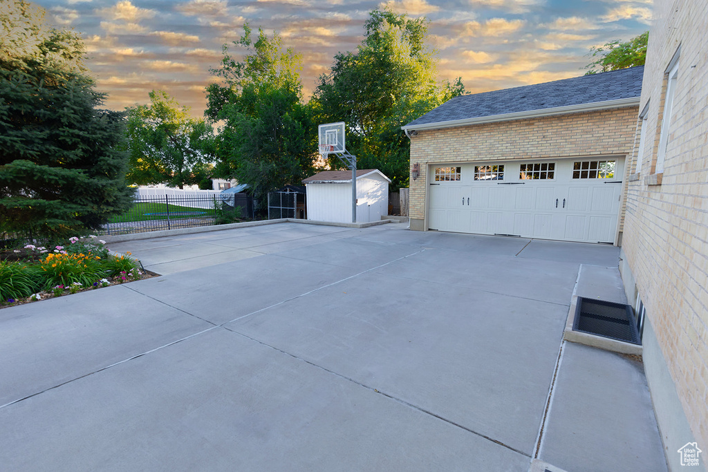 Patio terrace at dusk with a garage and a shed