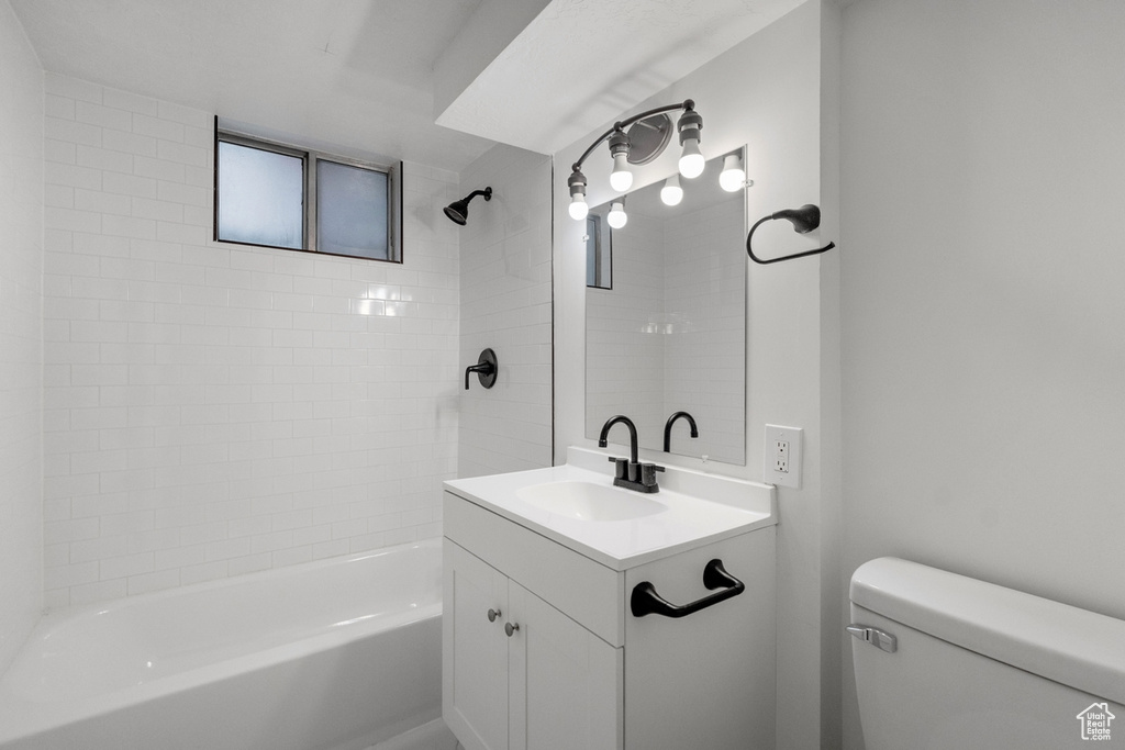 Full bathroom with vanity, tiled shower / bath combo, and toilet