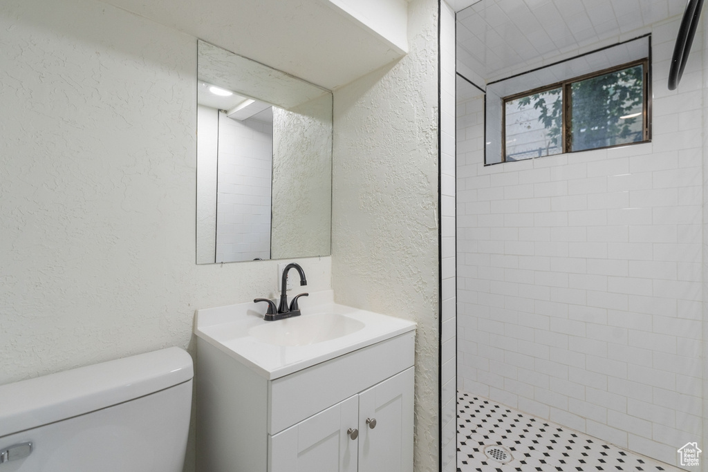 Bathroom with toilet, vanity, and a tile shower