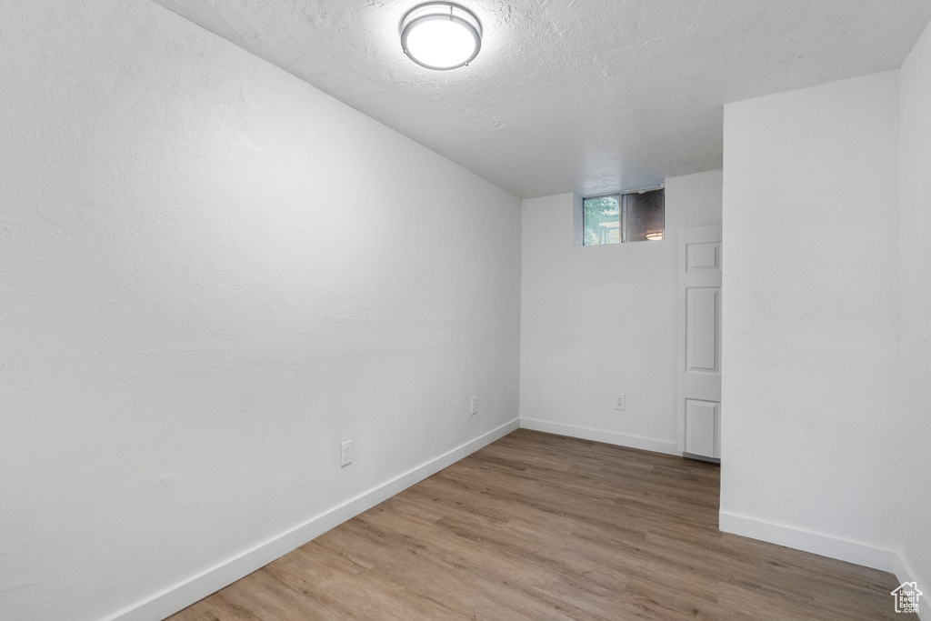 Basement with a textured ceiling and hardwood / wood-style floors