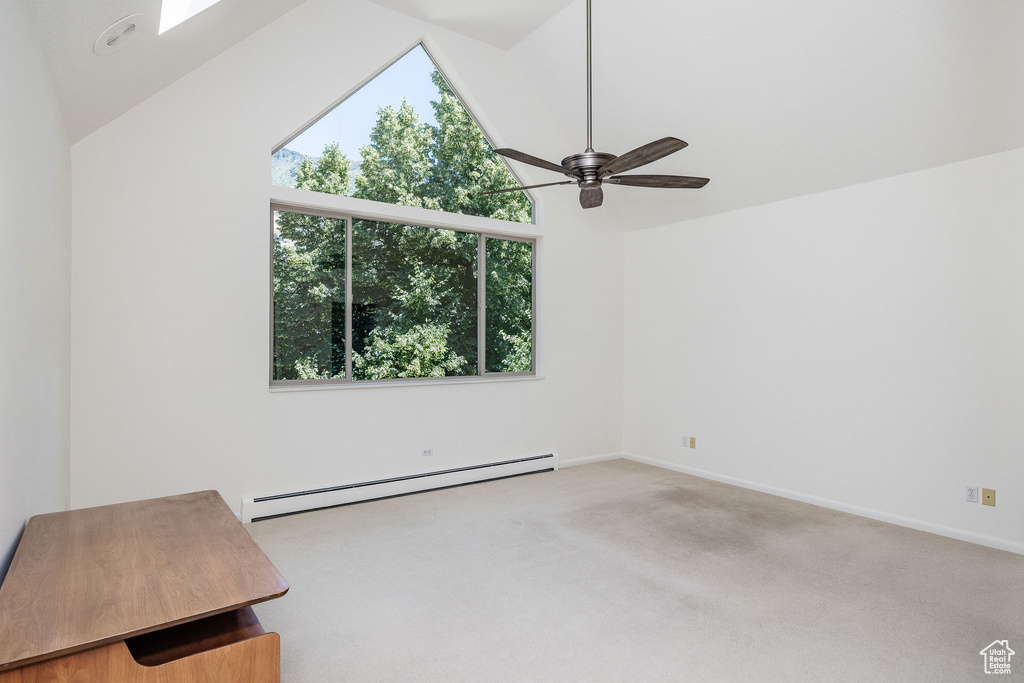 Carpeted empty room with ceiling fan, a baseboard heating unit, and high vaulted ceiling