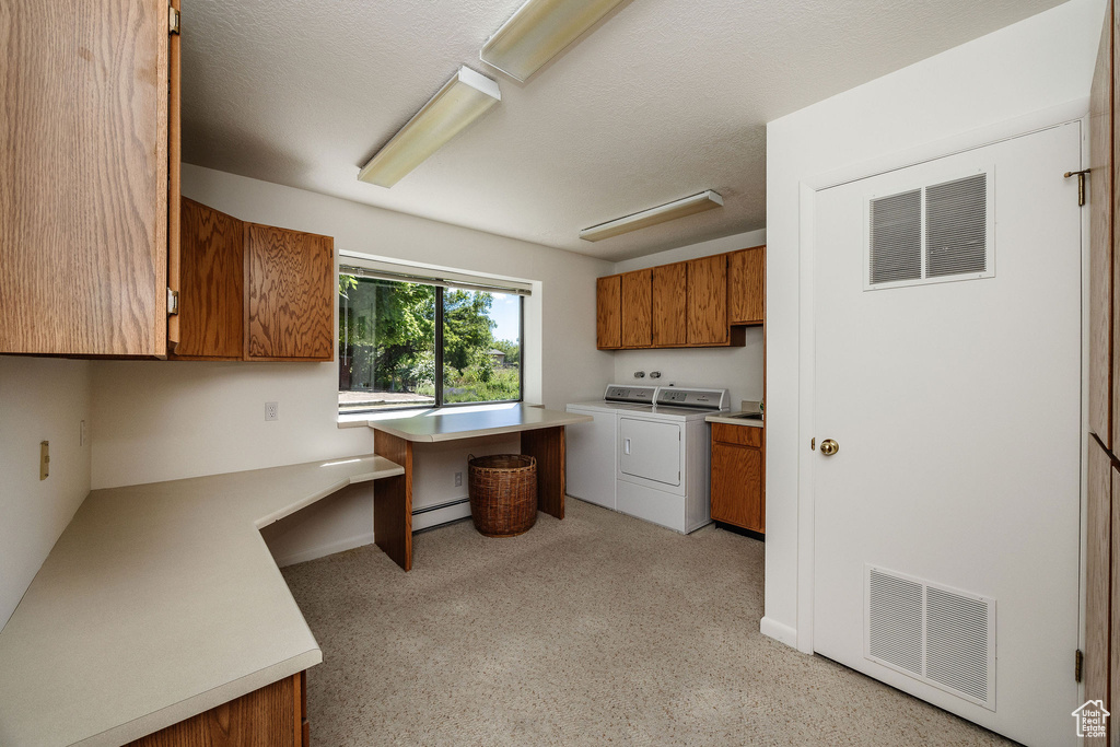 Kitchen featuring washer and dryer, a baseboard heating unit, and built in desk