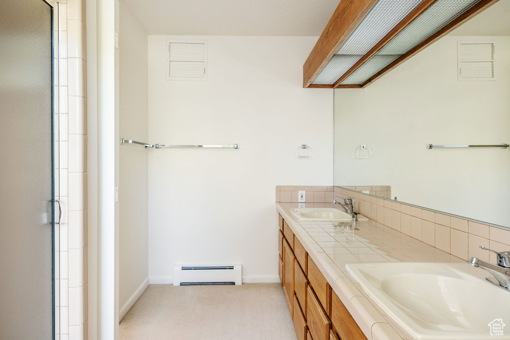 Bathroom featuring double vanity and a baseboard heating unit