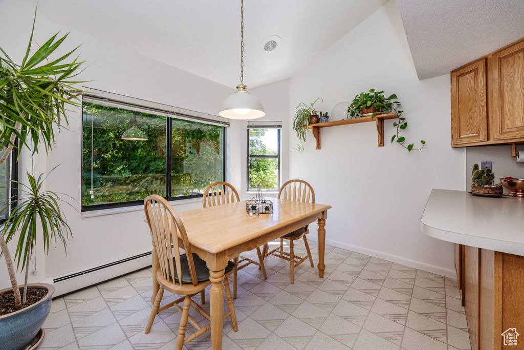 Dining room featuring a textured ceiling, baseboard heating, light tile patterned floors, and vaulted ceiling