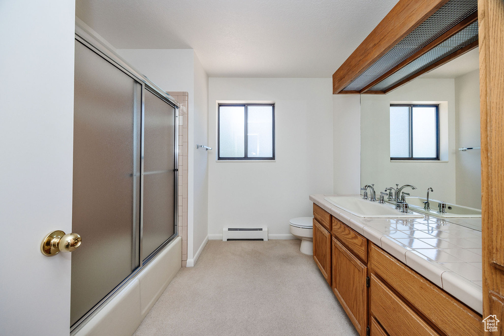 Full bathroom featuring a healthy amount of sunlight, baseboard heating, toilet, and vanity