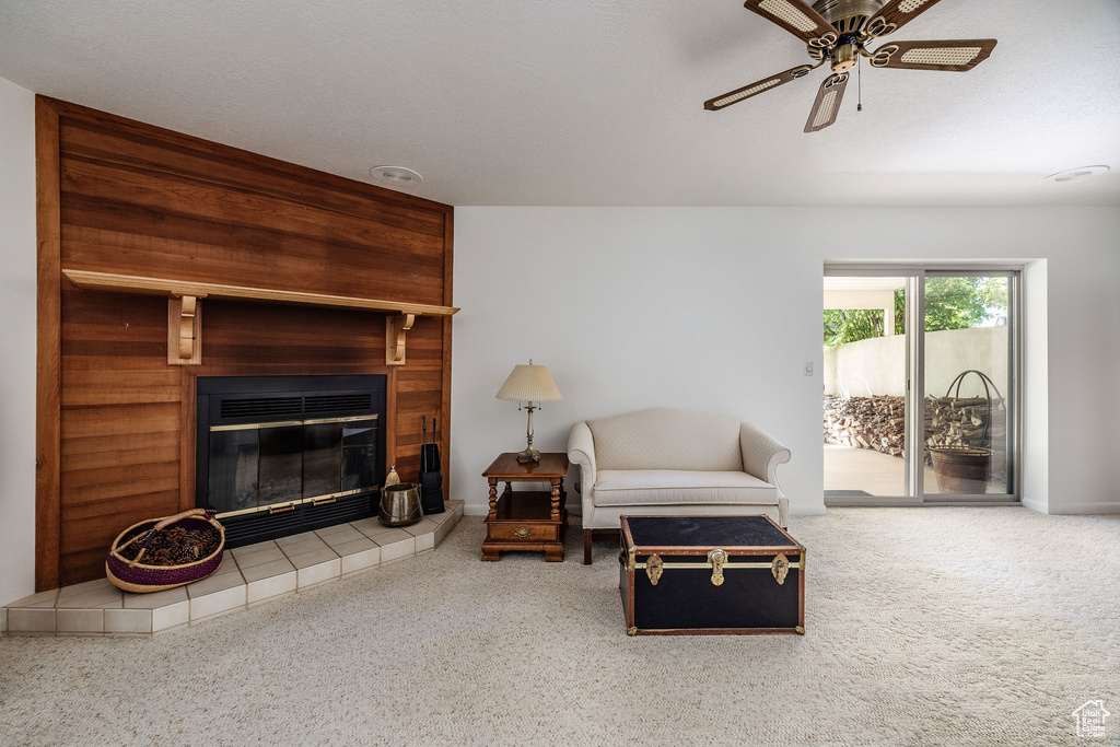 Living room featuring carpet flooring, a tiled fireplace, and ceiling fan