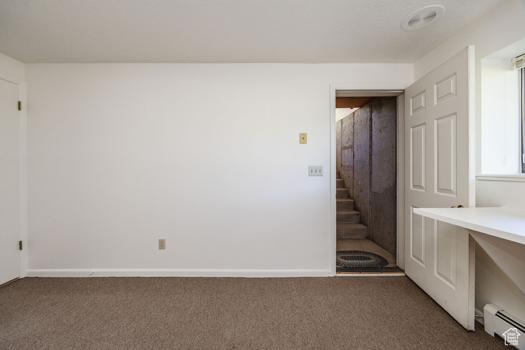 Unfurnished bedroom featuring carpet and a baseboard radiator