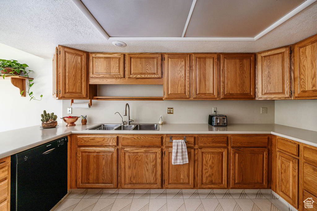 Kitchen featuring sink, dishwasher, a textured ceiling, and light tile patterned floors