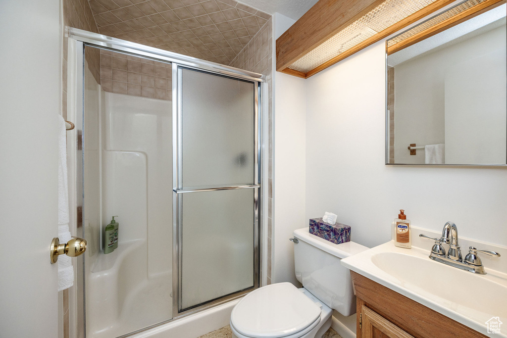 Bathroom featuring vanity, walk in shower, and toilet