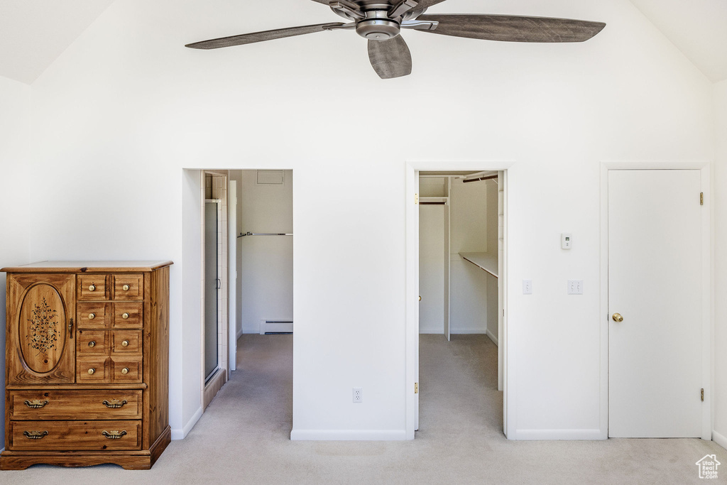 Unfurnished bedroom with light carpet, a baseboard radiator, ceiling fan, and high vaulted ceiling