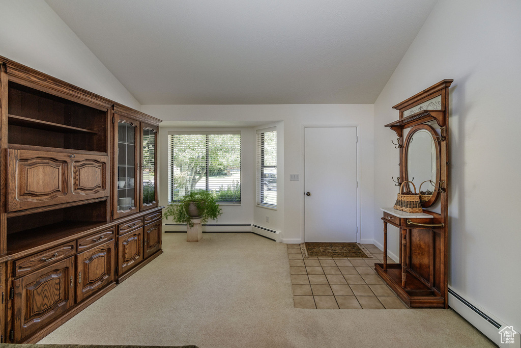 Foyer featuring a baseboard radiator, light colored carpet, and vaulted ceiling