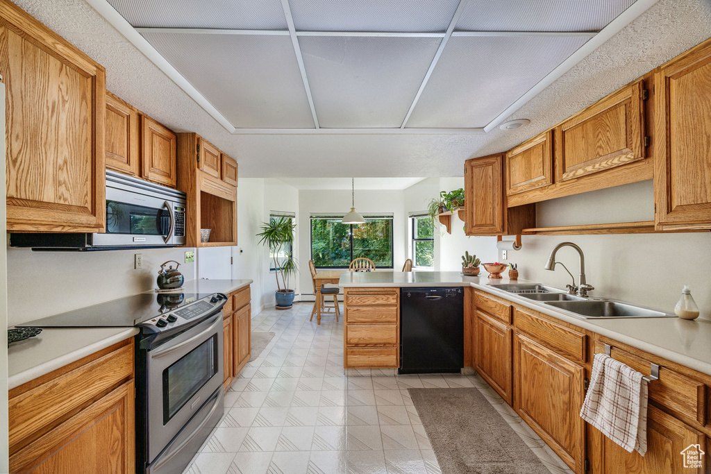 Kitchen featuring light tile patterned flooring, kitchen peninsula, stainless steel appliances, pendant lighting, and sink