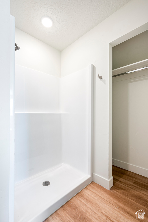 Bathroom featuring a shower, wood-type flooring, and a textured ceiling