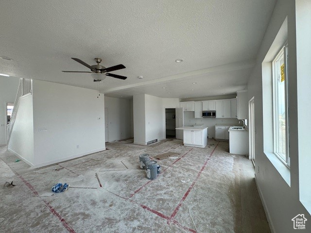 Unfurnished living room with sink, a textured ceiling, and ceiling fan