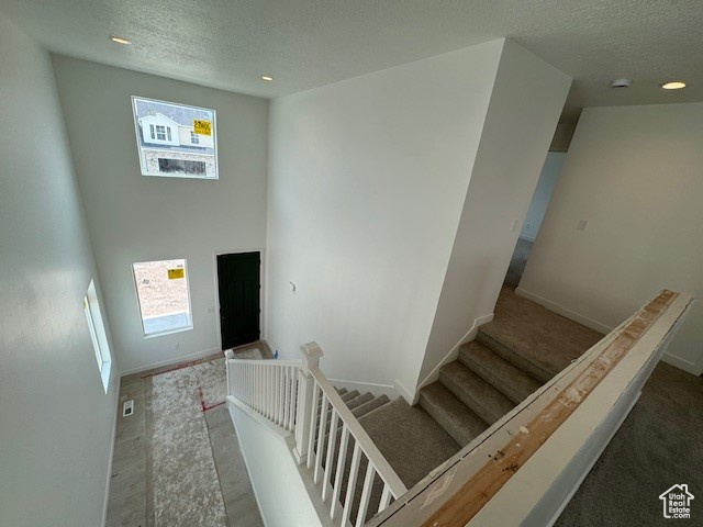 Stairway featuring a textured ceiling