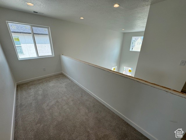 Carpeted empty room featuring a textured ceiling