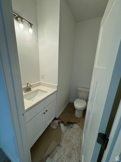 Bathroom featuring tile patterned flooring, toilet, vanity, and a textured ceiling