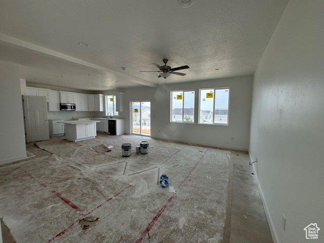 Unfurnished living room featuring a textured ceiling and ceiling fan