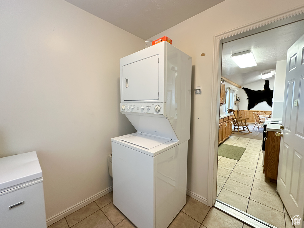 Washroom featuring stacked washer / dryer and light tile patterned floors