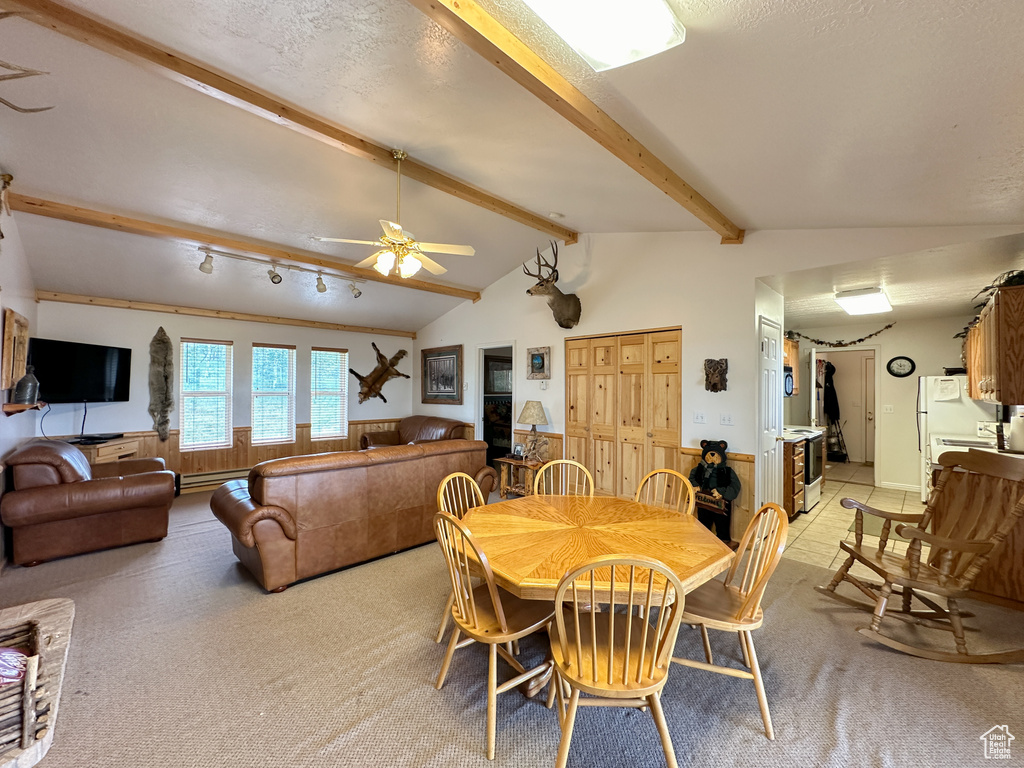 Dining room featuring lofted ceiling with beams, carpet, and ceiling fan