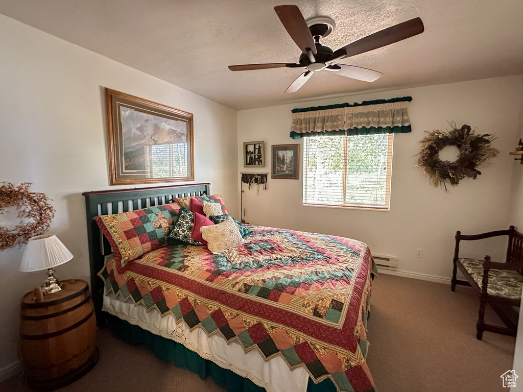 Bedroom with carpet, ceiling fan, and baseboard heating