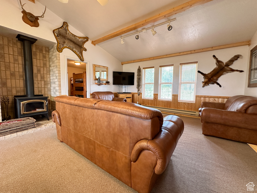 Living room featuring carpet floors, rail lighting, lofted ceiling with beams, and a wood stove