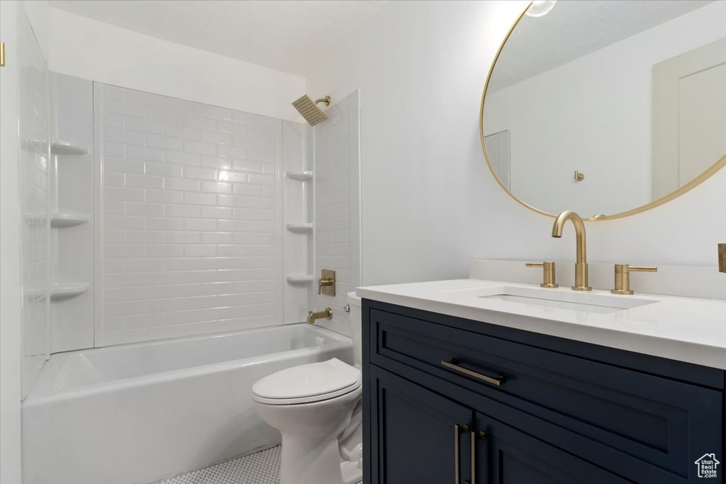 Full bathroom with washtub / shower combination, tile patterned floors, toilet, and vanity