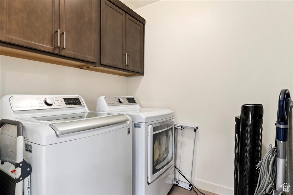 Washroom with cabinets and washer and clothes dryer