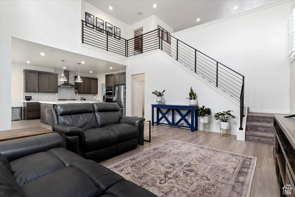 Living room with light hardwood / wood-style flooring, sink, and a high ceiling