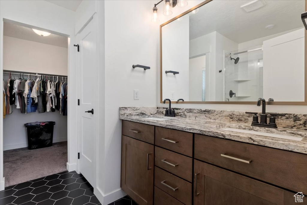 Bathroom with tile patterned flooring, dual vanity, and walk in shower