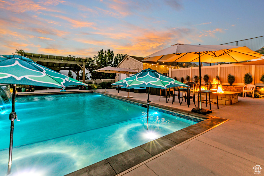 Pool at dusk with a pergola, a patio area, and an outdoor fire pit