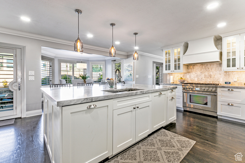 Kitchen featuring white cabinetry, custom range hood, dark hardwood / wood-style flooring, high end stainless steel range oven, and sink