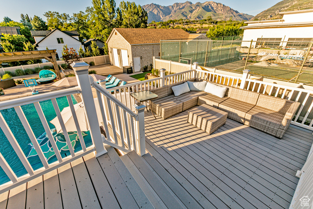 Deck featuring a pergola, a pool, an outdoor hangout area, a mountain view, and a shed