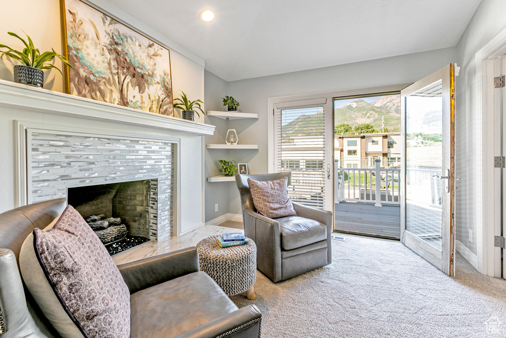 Living area featuring light carpet and a tiled fireplace