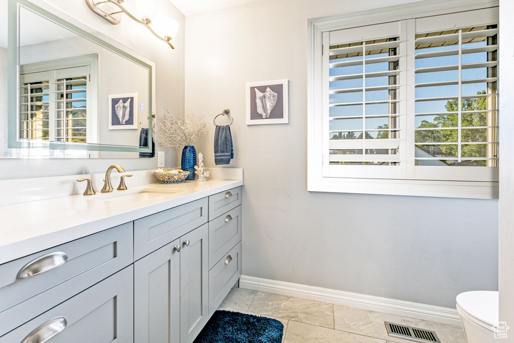 Bathroom featuring vanity, toilet, tile patterned flooring, and plenty of natural light