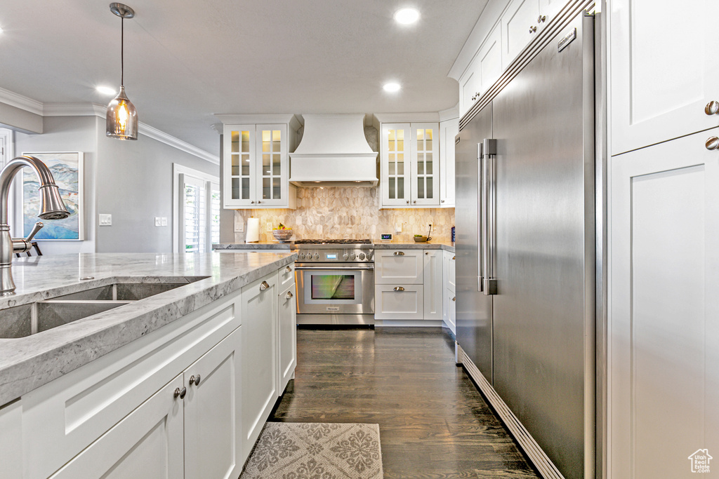 Kitchen with custom exhaust hood, hanging light fixtures, white cabinets, dark hardwood / wood-style floors, and high end appliances