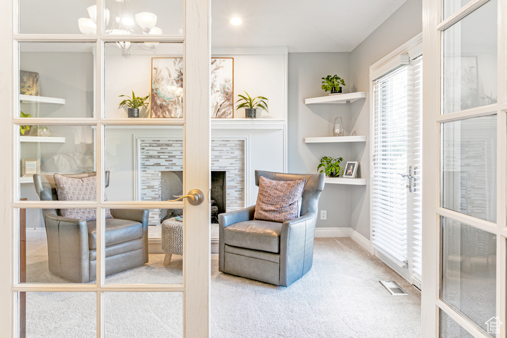 Sitting room with built in shelves, carpet, and an inviting chandelier