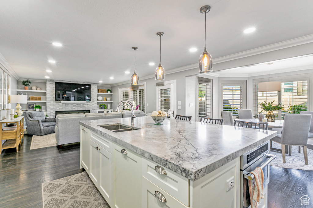 Kitchen featuring white cabinets, wood-type flooring, a kitchen island with sink, and sink