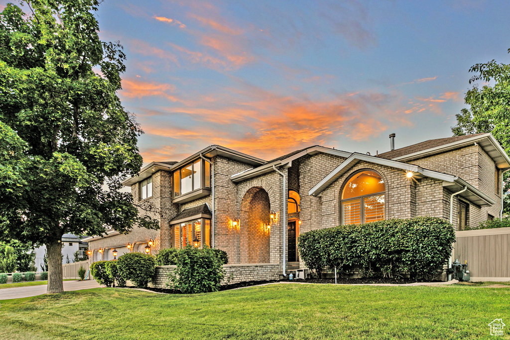 View of front of property featuring central air condition unit and a lawn