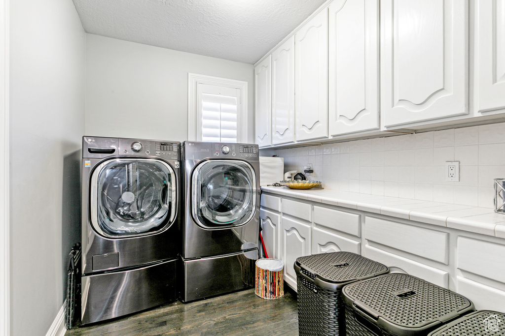 Clothes washing area with separate washer and dryer, hardwood / wood-style floors, cabinets, and a textured ceiling